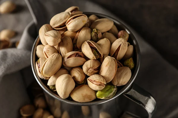 Mug with tasty pistachio nuts on table, closeup — Stock Photo, Image