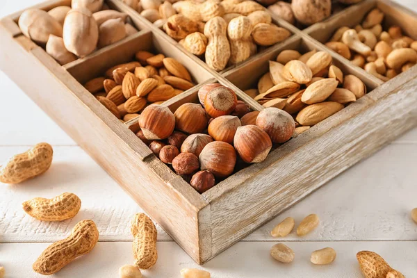 Box with different tasty nuts on white table