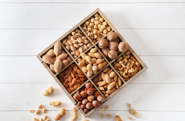 Box with different tasty nuts on white table