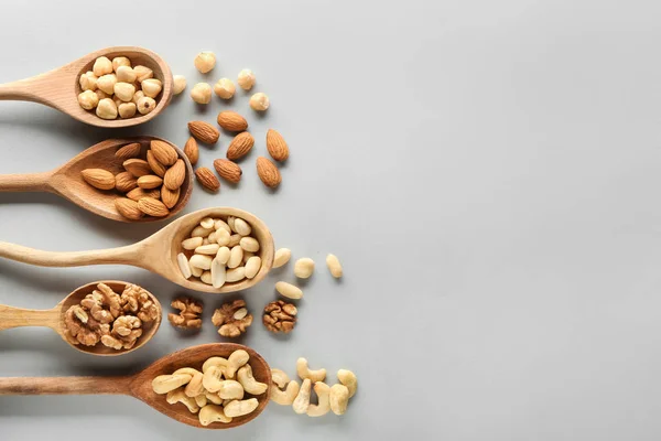Spoons with different tasty nuts on light background — Stock Photo, Image