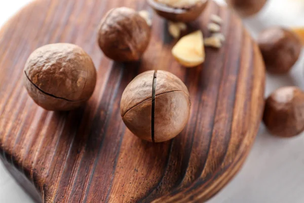 Tasty macadamia nuts on wooden board, closeup — Stock Photo, Image
