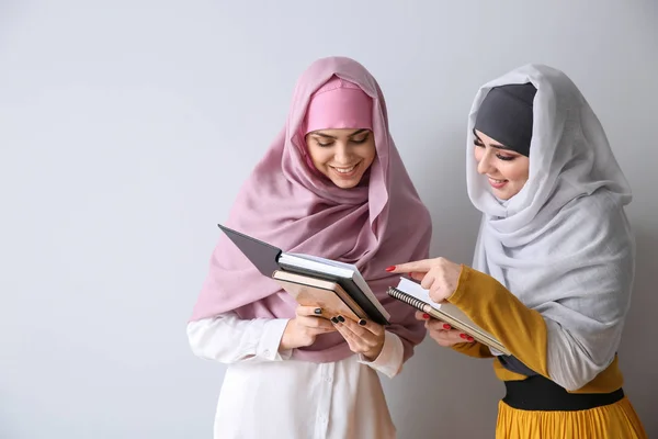 Junge muslimische Frauen mit Büchern auf hellem Hintergrund — Stockfoto