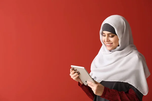 色の背景にタブレットコンピュータを持つイスラム教徒の女性 — ストック写真