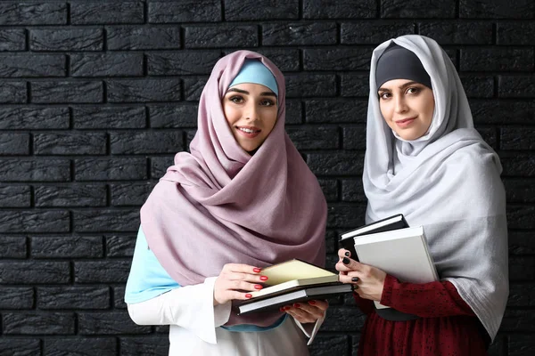 Muslim women with books on dark background — Stock Photo, Image