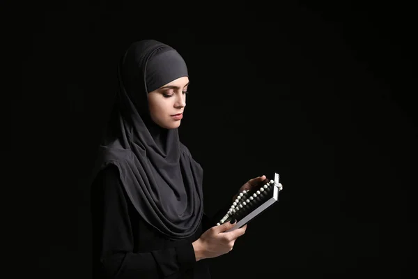 Muslimische Frau mit Koran und Tasbih auf dunklem Hintergrund — Stockfoto