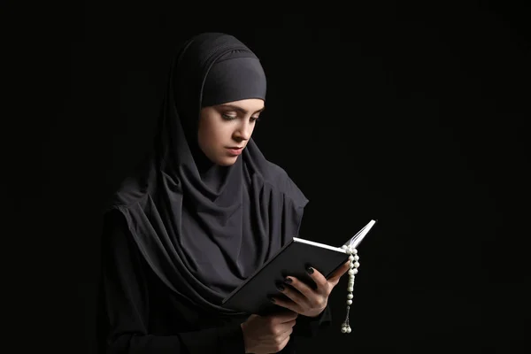 Muslimische Frau mit Koran und Tasbih auf dunklem Hintergrund — Stockfoto