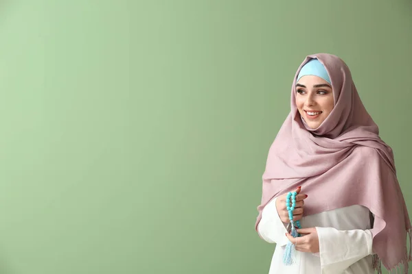 Muslim woman with tasbih on color background — Stock Photo, Image