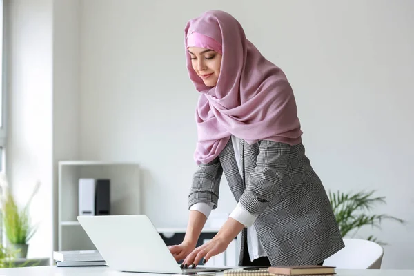 Muslimsk kvinna som arbetar på laptop på kontoret — Stockfoto