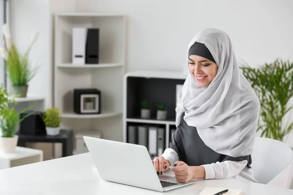 Muslimsk kvinna som arbetar på laptop på kontoret — Stockfoto