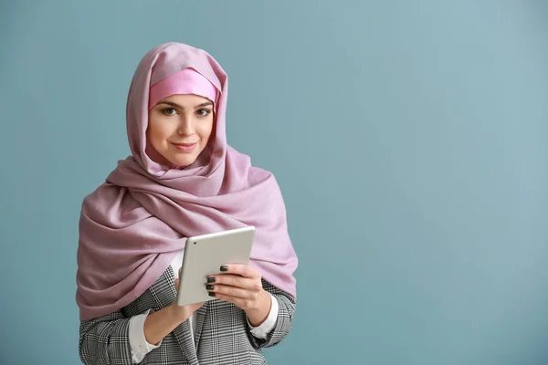 Wanita muslim muda dengan komputer tablet pada latar belakang warna — Stok Foto