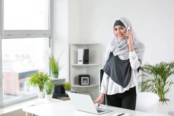 Muslimsk kvinna pratar per telefon medan du arbetar i Office — Stockfoto