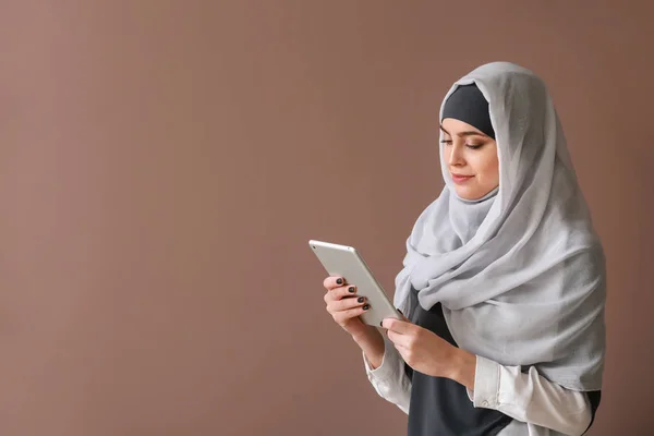 Mujer musulmana joven con Tablet PC sobre fondo de color —  Fotos de Stock