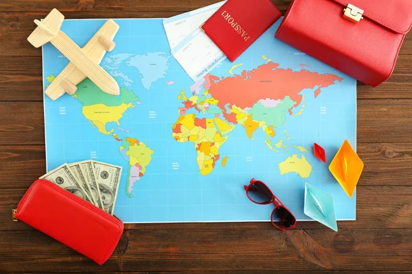 World map with money, passport, tickets and female accessories on wooden table. Travel concept