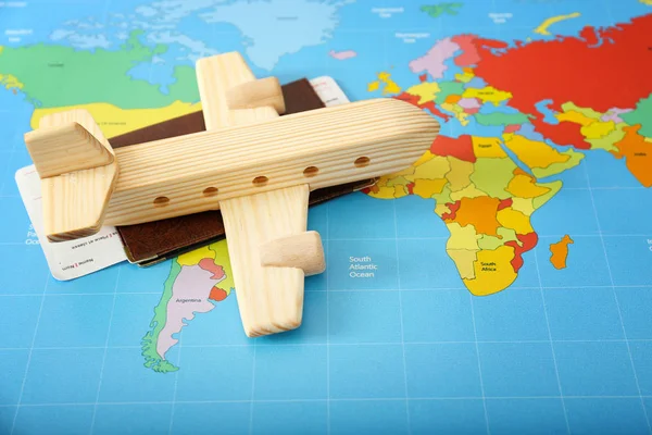 Drewniany samolot z paszportem i biletami na mapie świata. Koncepcja podróży — Zdjęcie stockowe
