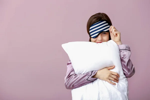 Sleepy woman with mask and pillow on color background — Stock Photo, Image