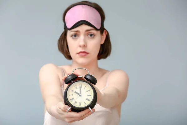 Sad woman with sleep mask and alarm clock on color background — Stock Photo, Image
