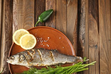 Ahşap masada lezzetli pişmiş balık ile plaka