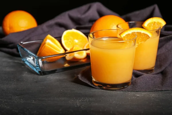 Vasos de jugo de naranja recién exprimido sobre mesa oscura —  Fotos de Stock