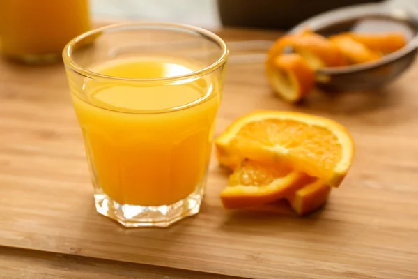 Γυαλί του φρεσκοστυμμένο χυμό πορτοκαλιού σε ξύλινο τραπέζι — Φωτογραφία Αρχείου