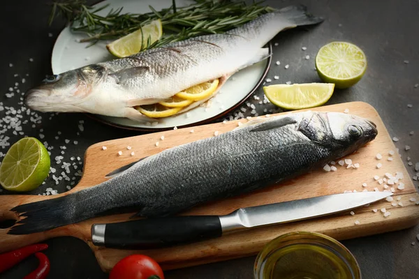 Preparing of tasty fresh fish on dark table — Stock Photo, Image