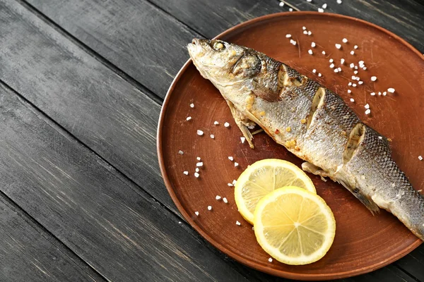 Assiette avec savoureux poisson cuit sur table en bois — Photo