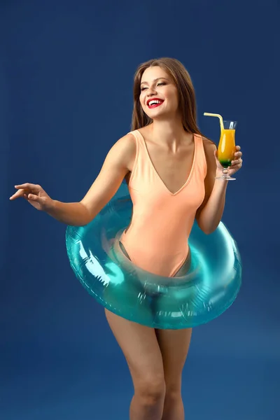 Piękna młoda kobieta z nadmuchiwanym pierścieniem i koktajlem na kolorowym tle — Zdjęcie stockowe