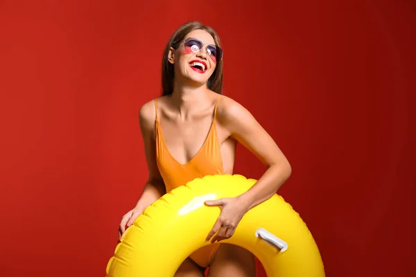 Mooie jonge vrouw met opblaasbare ring op kleur achtergrond — Stockfoto