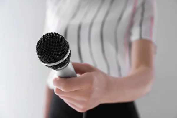 Giornalista donna con microfono su sfondo chiaro, primo piano — Foto Stock