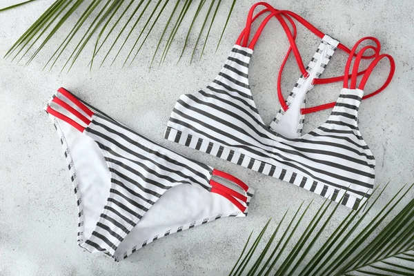 Hafif arka planda şık kadın mayo ve tropikal yaprakları