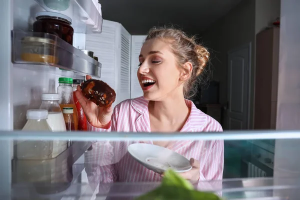 愉快的年轻妇女选择食物在冰箱里, 从里面看 — 图库照片