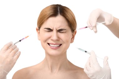 Beyaz arka planda yaşlanma karşıtı enjeksiyonlar için şırıngalar tutan korkmuş kadın ve eller