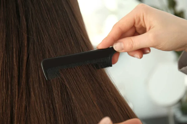 Peluquería peinando pelo largo de mujer joven en el salón — Foto de Stock