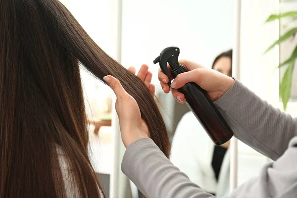 Parrucchiere che lavora con capelli lunghi di giovane donna in salone — Foto Stock