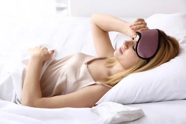 Woman with sleep mask lying in bed — Stock Photo, Image