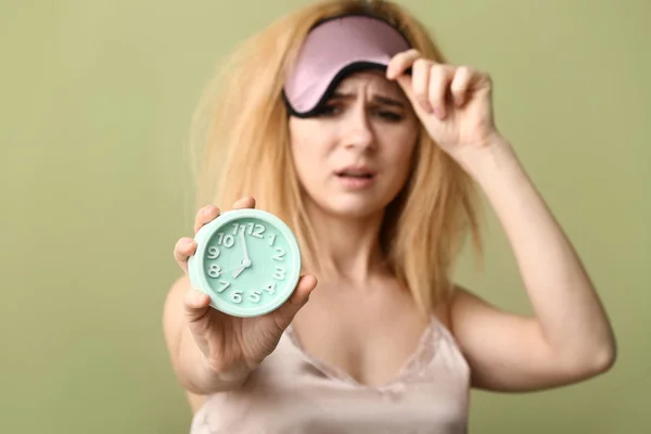 Slaperige vrouw met masker en klok op kleur achtergrond — Stockfoto