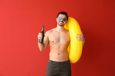 Renkli arka planda şişme yüzük ve bira ile yakışıklı adam