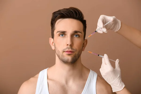 Csinos férfi és kéz gazdaság fecskendők az anti-aging injekciót a színes háttér — Stock Fotó