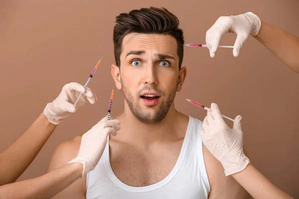 Scared mężczyzna i ręce trzymając strzykawki do Anti-Aging zastrzyki na kolorowym tle — Zdjęcie stockowe