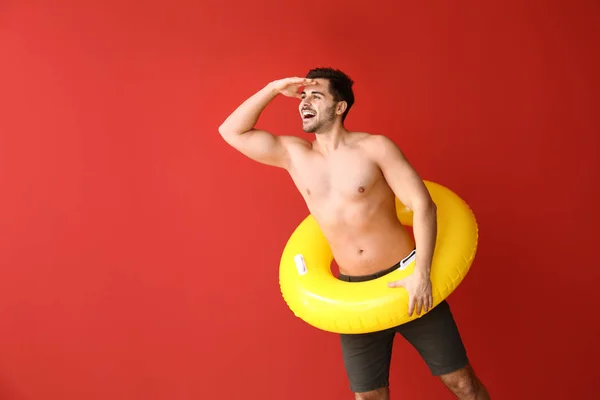 Homem bonito com anel inflável no fundo da cor — Fotografia de Stock