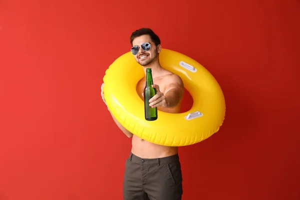 Homem bonito com anel inflável e cerveja no fundo da cor — Fotografia de Stock