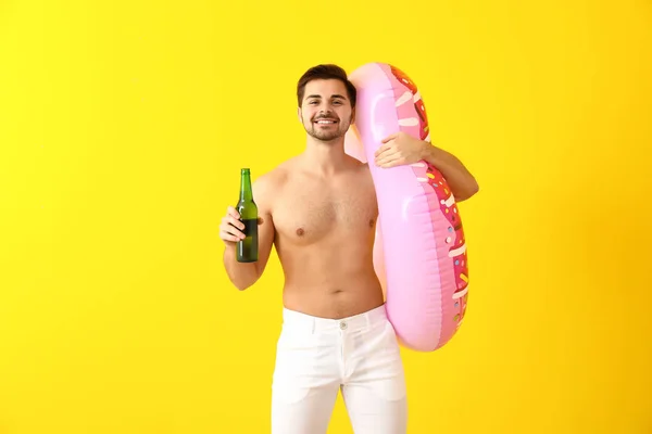 Красивый мужчина с надувным кольцом и пивом на цветном фоне — стоковое фото