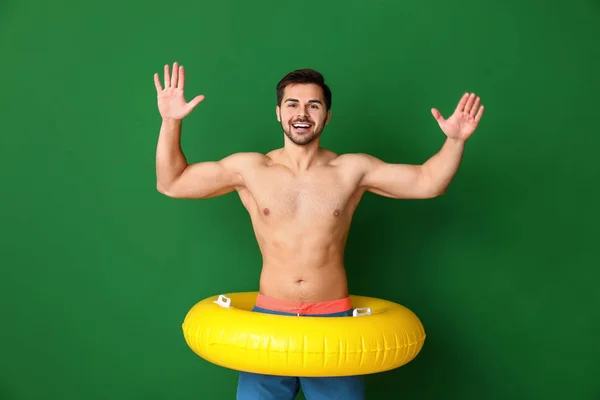 Handsome man with inflatable ring on color background — Stock Photo, Image