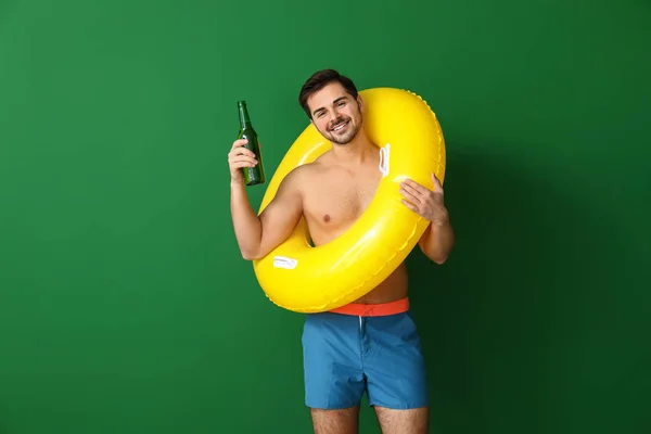 Bel homme avec anneau gonflable et bière sur fond de couleur — Photo