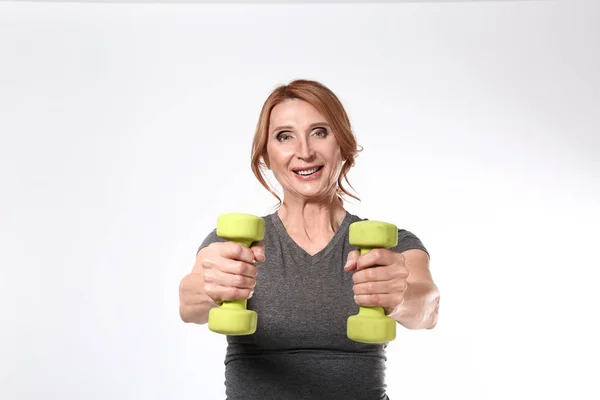 Sporty mature woman with dumbbells on white background — Stock Photo, Image