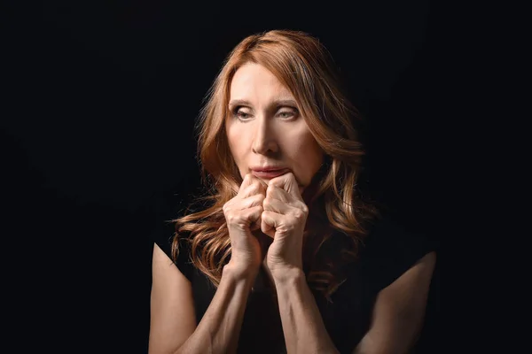 Thoughtful mature woman on dark background — Stock Photo, Image