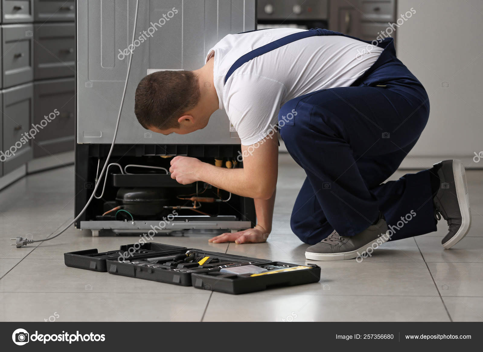 Male technician repairing refrigerator in kitchen Stock Photo by