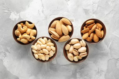 Gri arka planda farklı lezzetli fındık ile kase