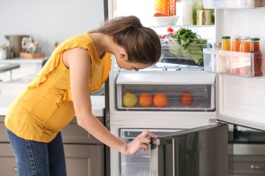 Hamile kadın evde buzdolabından yemek alıyor
