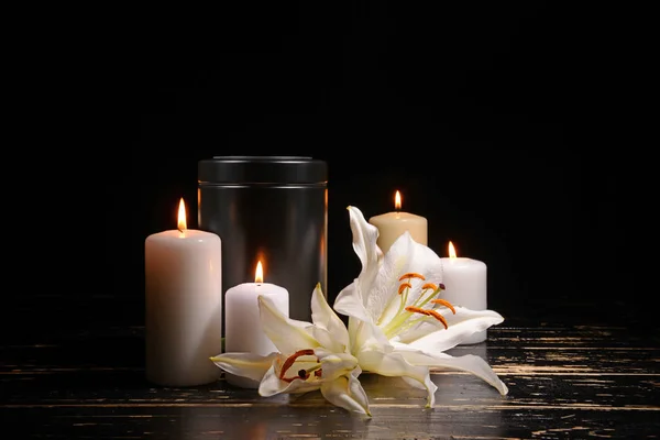 Urna mortuoria, velas encendidas y flores sobre la mesa sobre fondo oscuro —  Fotos de Stock