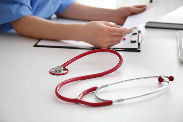 Estetoscópio e médico trabalhando à mesa — Fotografia de Stock